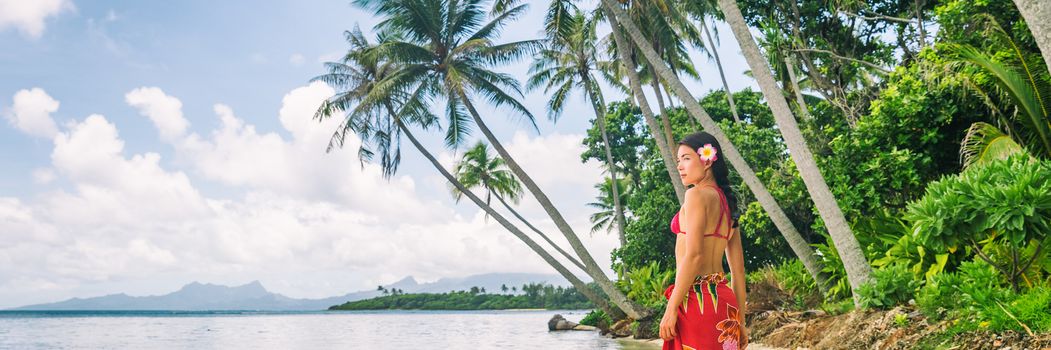 Tahiti luxury exotic travel vacation girl with polynesian flower walking on beach landscape with palm trees. Asian woman in red bikini and beachwear banner panorama.