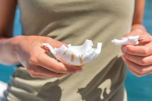 Fresh coconut pieces of flesh. Closeup of woman's hands holding chunks of fruit cut by local at tropical travel destination. Coco water, toasted slices are very popular healthy food trend for health.