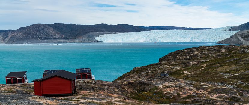 Greenland glacier nature landscape with famous Eqi glacier and lodge cabins. Tourist destination Eqi glacier in West Greenland AKA Ilulissat and Jakobshavn Glacier. Heavlly affected by Global Warming.