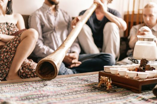 the tea ceremony is conducted by a tea master. tea party in the style of boho, hippie. tea cups on a special wooden coffee table. Preparation of masala tea. a didgeridoo. Tea is prepared on the fire.