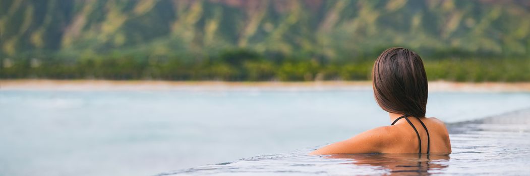 Luxury vacation woman travel tourist relaxing in infinity swimming pool on summer travel at tropical beach resort. girl alone on wellness spa relaxation outside in nature landscape banner panorama.