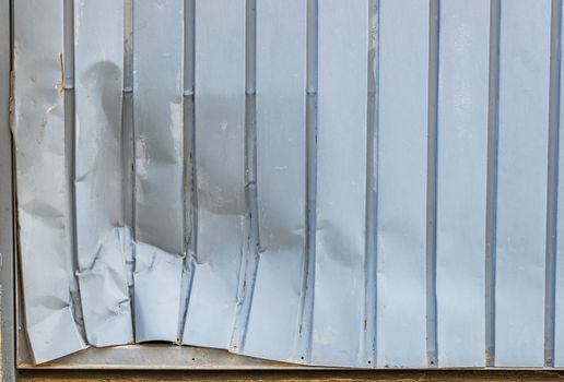 Close-up of dented gray garage metal door