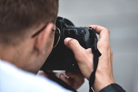 Digital single-lens reflex camera in hands. Photographer shooting hands close up. Man photographer makes photos for stock photography. Male hands hold the camera close-up