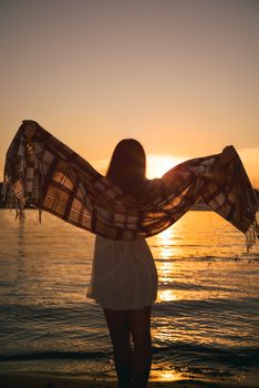 girl standing on the beach, watching the sunset