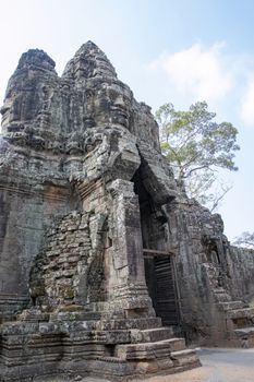 Cambodia, Bayon Temple - March 2016: The temple bridge is a main through road for traffic. Carved like the Bayon temple with a multitude of serene and smiling stone faces 