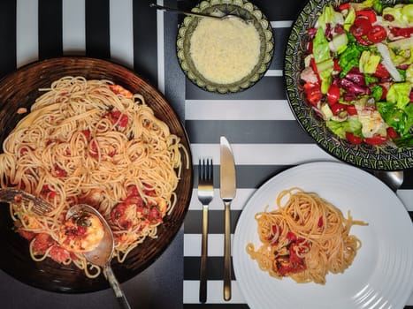Top view of Spaghetti seafood on a bowl with tomato sauce served with a fork & spoon on a white dish.
