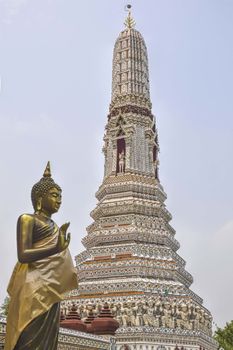 THAILAND, BANGOK - 28 MARCH 2016 - Buddha statue near the spire of a pagoda at the temple of dawn, wat arun