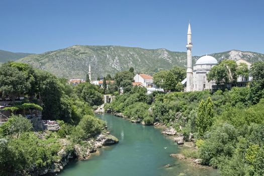 Bosnia and Herzegovina, Mostar - June 2018: The Koski Mehmed Pasha Mosque as seen from the old bridge. Substantially rebuilt after the war, this 1618 domed mosque has a minaret that gives views over the town