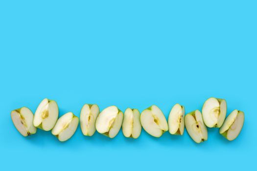 Green apple slices on blue background. Copy space