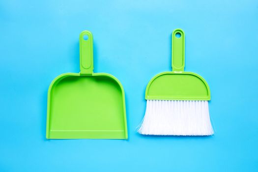 A broom and dustpan on blue background. Top view