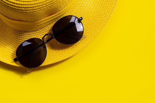 Sunglasses with summer hat on yellow background. Enjoy holiday concept. Copy space