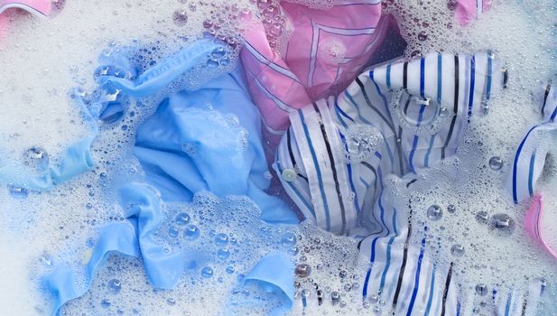 Top view of color clothes soak in powder detergent water dissolution. Laundry concept