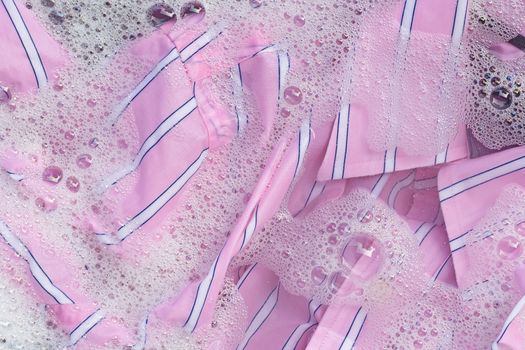 Top view of color clothes soak in powder detergent water dissolution. Laundry concept