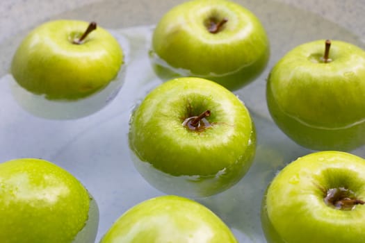 Soak fresh green apples in water. Washing fruit concept