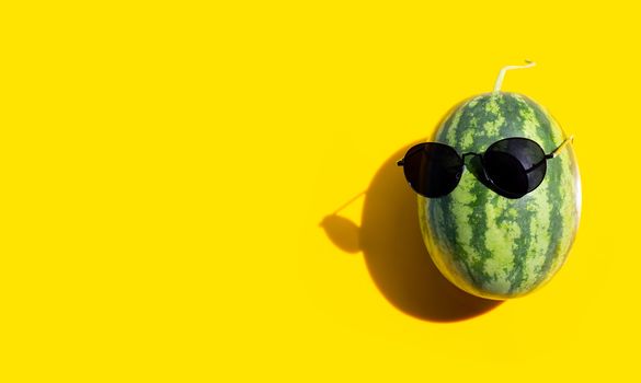 Watermelon with sunglasses on yellow background. Enjoy summer holiday concept. Copy space