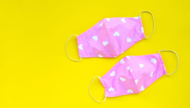 Handmade pink and heart shape cloth masks on yellow background. Copy space