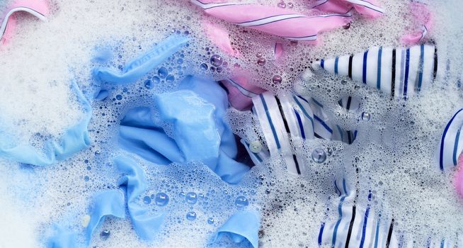 Top view of color clothes soak in powder detergent water dissolution. Laundry concept