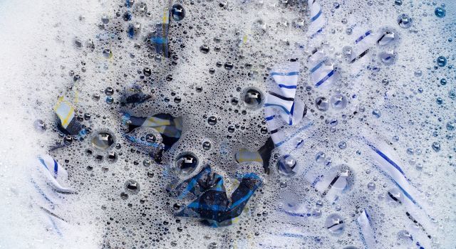 Top view of clothes soak in powder detergent water dissolution. Laundry concept