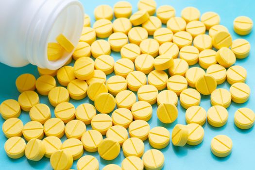 Yellow tablets of Paracetamol on blue background.