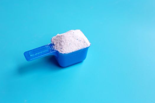 Detergent powder with measuring spoon  for clothes washing. Laundry concept. Blue background. Top view