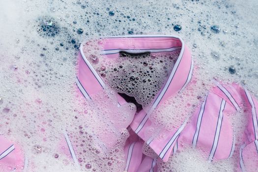 Top view of color clothes soak in powder detergent water dissolution. Laundry concept