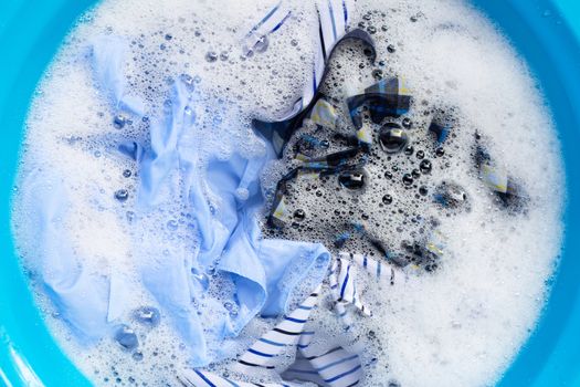 Top view of clothes soak in powder detergent water dissolution. Laundry concept