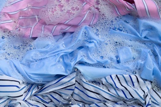 Top view of color clothes soak in powder detergent water dissolution. Laundry concept