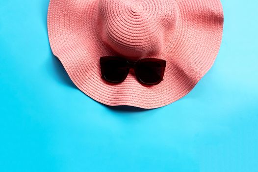 Sunglasses with summer hat on blue background. Enjoy holiday concept. Copy space
