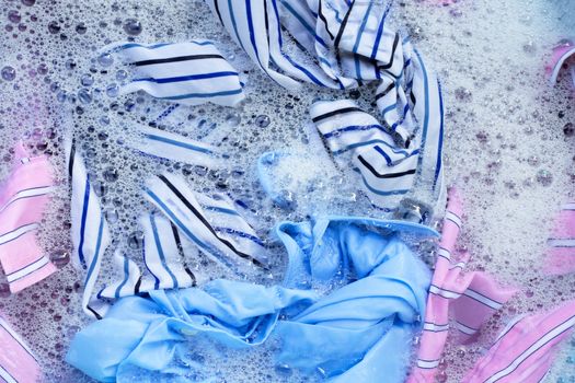 Top view of color clothes soak in powder detergent water dissolution. Laundry concept