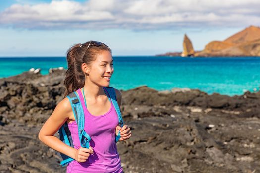 Galapagos tourist on Santiago Island in Galapagos Islands. Pinnacle Rock and Bartolome Island in background. Famous Galapagos cruise ship tour destination.