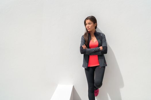 Activewear Asian girl model woman leaning on wall in yoga leggings and running jacket ready to train at gym. Active lifestyle healthy people.