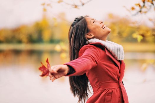 Autumn woman happy smiling feeling free in fall nature. Nature people beauty landscape. Girl by the lake.