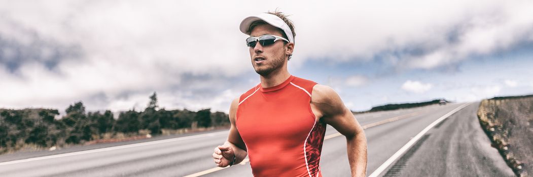 Triathlon runner man running on road panoramic backbround. Fit athlete jogging on competition race. Triathlete training for marathon banner panorama.