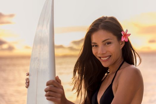 Beach sunset sexy surfer woman surfing lifestyle relaxing holding surfboard for surf. Active healthy cute Asian sports athlete girl smiling in colorful sky.