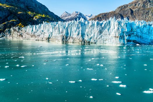 Glacier Bay Alaska cruise vacation travel. Global warming and climate change concept with melting ice. Cruising boat towards landscape of Johns Hopkins Glacier and Mount Fairweather Range mountains.