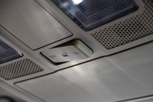 A switch on the roof of a car controlling the behavior of the interior lighting is switched to the "off" position.