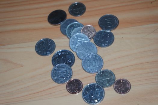 Silver shining Korean won coin scattered over a wooden floor.