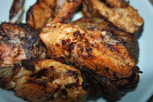 Spicy and crunchy barbecue of fried fish fillet on a white background. Homemade grilled trout fish steaks for health nourishments.