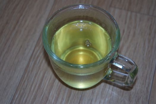 Glass cup having brewed fragrant green tea or qehwa or qahwa on the wooden floor. It is served with sugar or honey and nuts