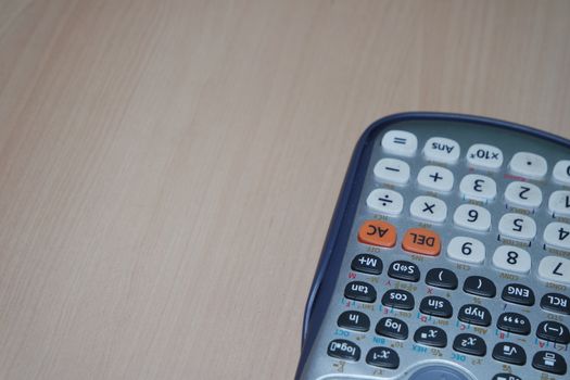 Calculator with colored keys or buttons isolated on a wooden background
