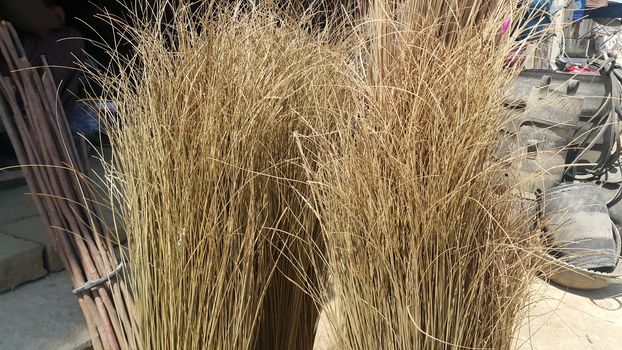 Bunch of brown colored straw broom. Old style broom used for housekeeping in rural area in Asian countries.