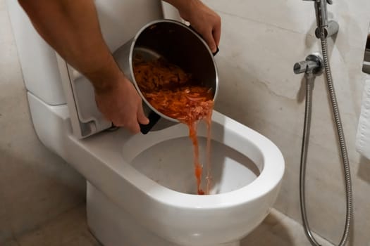 The girl pours a pot of soup into the toilet. Spoiled food.
