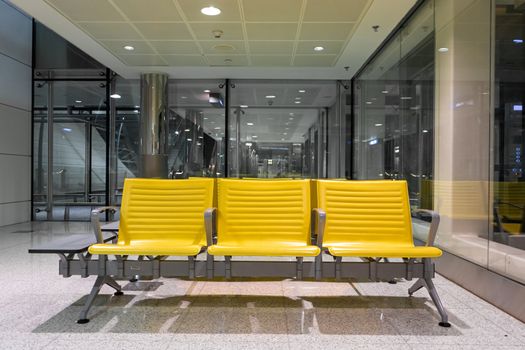 Rows of yellow benches in a waiting area at the airport