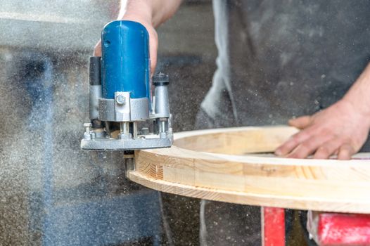 Milling of the Round wooden window using handheld electric cutters in joinery.