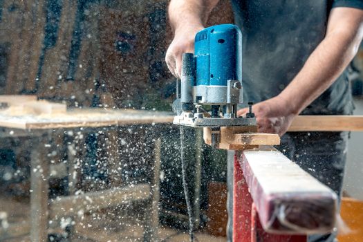 Milling wood in the joinery using manual mechanical cutters. Flying sawdust in the air. Copy space.