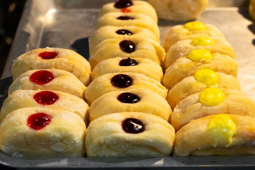 A showcase with pastries, rolls with colored fillers