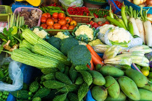 Fresh vegetables, fruits and greens on a counter in a street market.