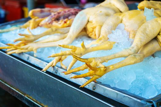 Asian yellow chicken carcasses on a display case with ice.