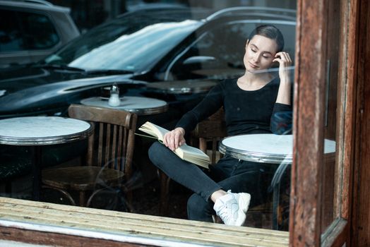 woman in coffee shop reading drinking cafe reading book in Paris