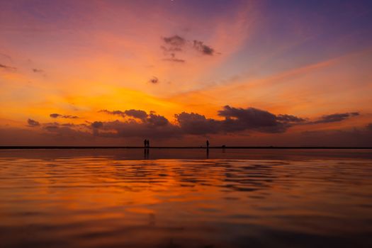 Burning bright sky during sunset on a tropical beach. Sunset during the exodus, the strength of people walking on water.